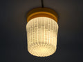 Vintage yellow ceiling light illuminated, showing a warm amber glow through the textured white glass shade.