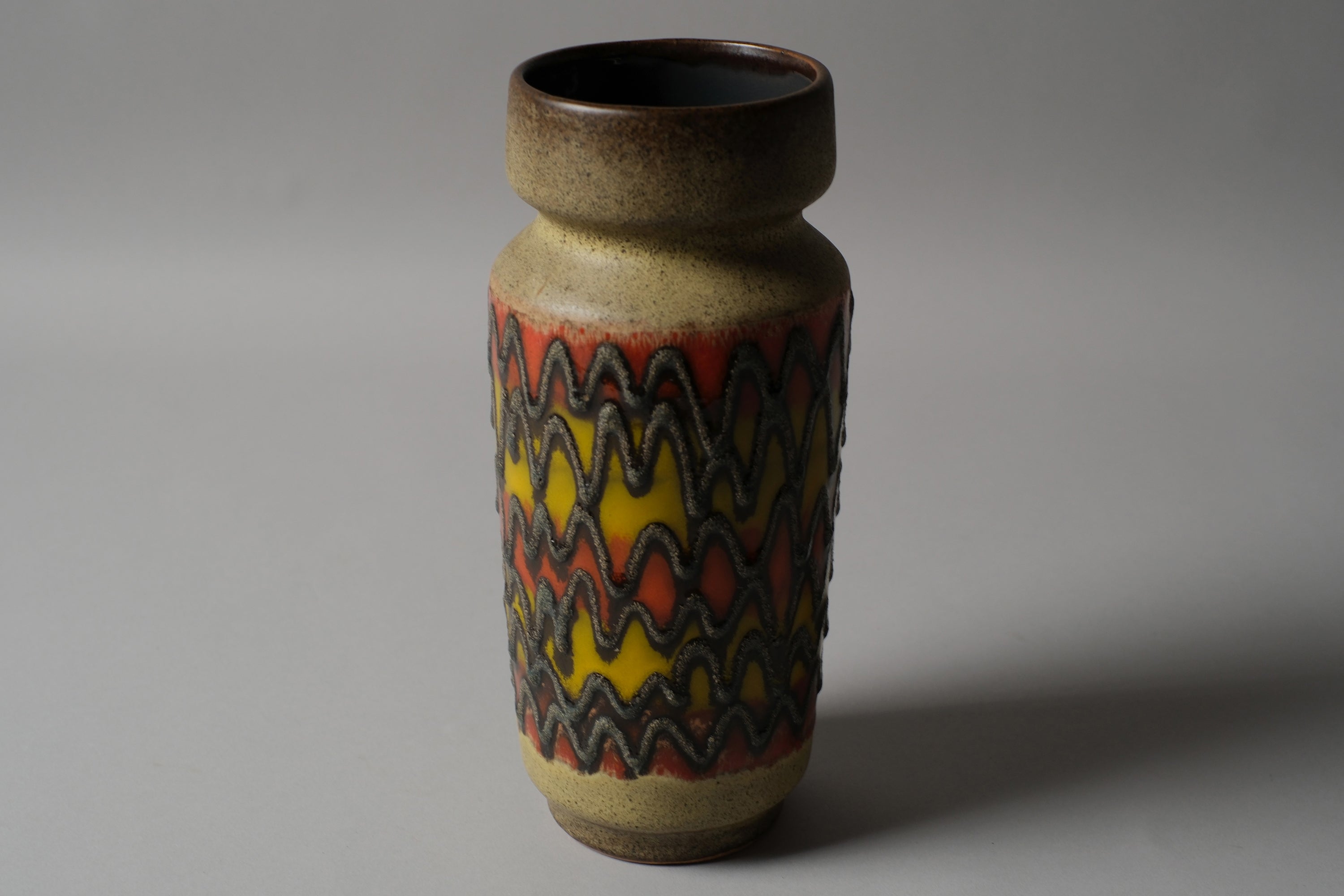 VEB Haldensleben fat lava vase, full height visible, cylindrical form with continuous zigzag band, orange yellow charcoal, 1960s GDR