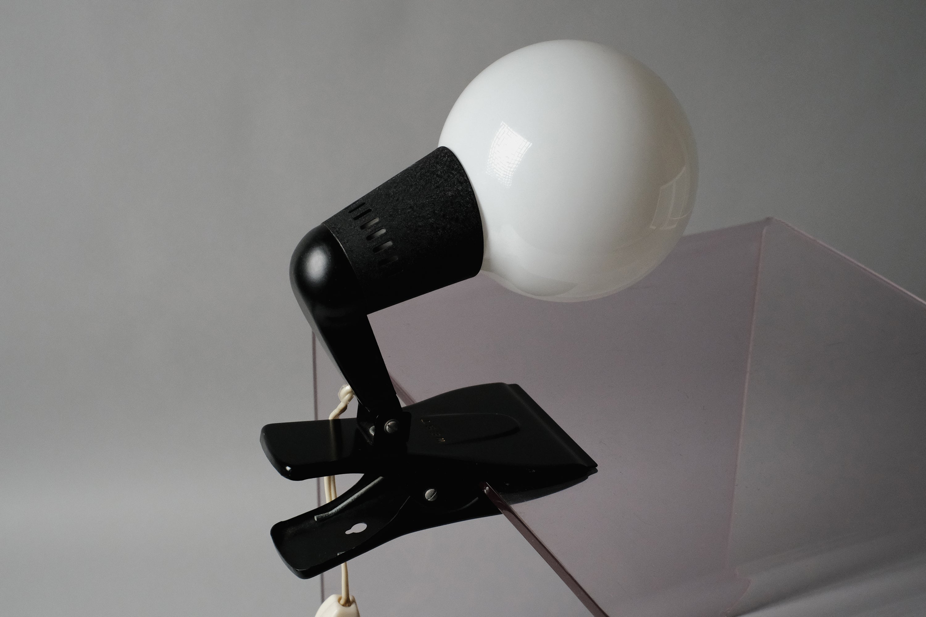 The vintage 1960s ERCO MCM clamp spotlight German industrial clip-on desk lamp centered against a neutral grey background to highlight its modernist form.