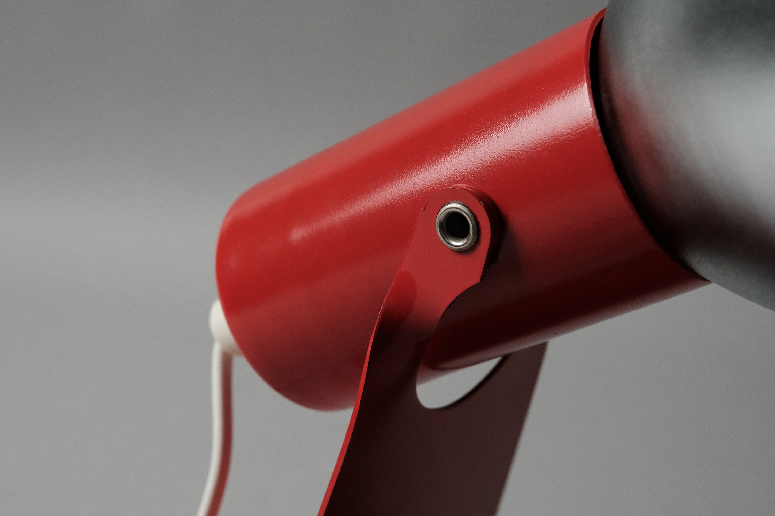 Close-up detail of the pivot point on the vintage 1970s Gnosjo Konstsmide Swedish MCM red metal industrial desk lamp for adjustable tilting.