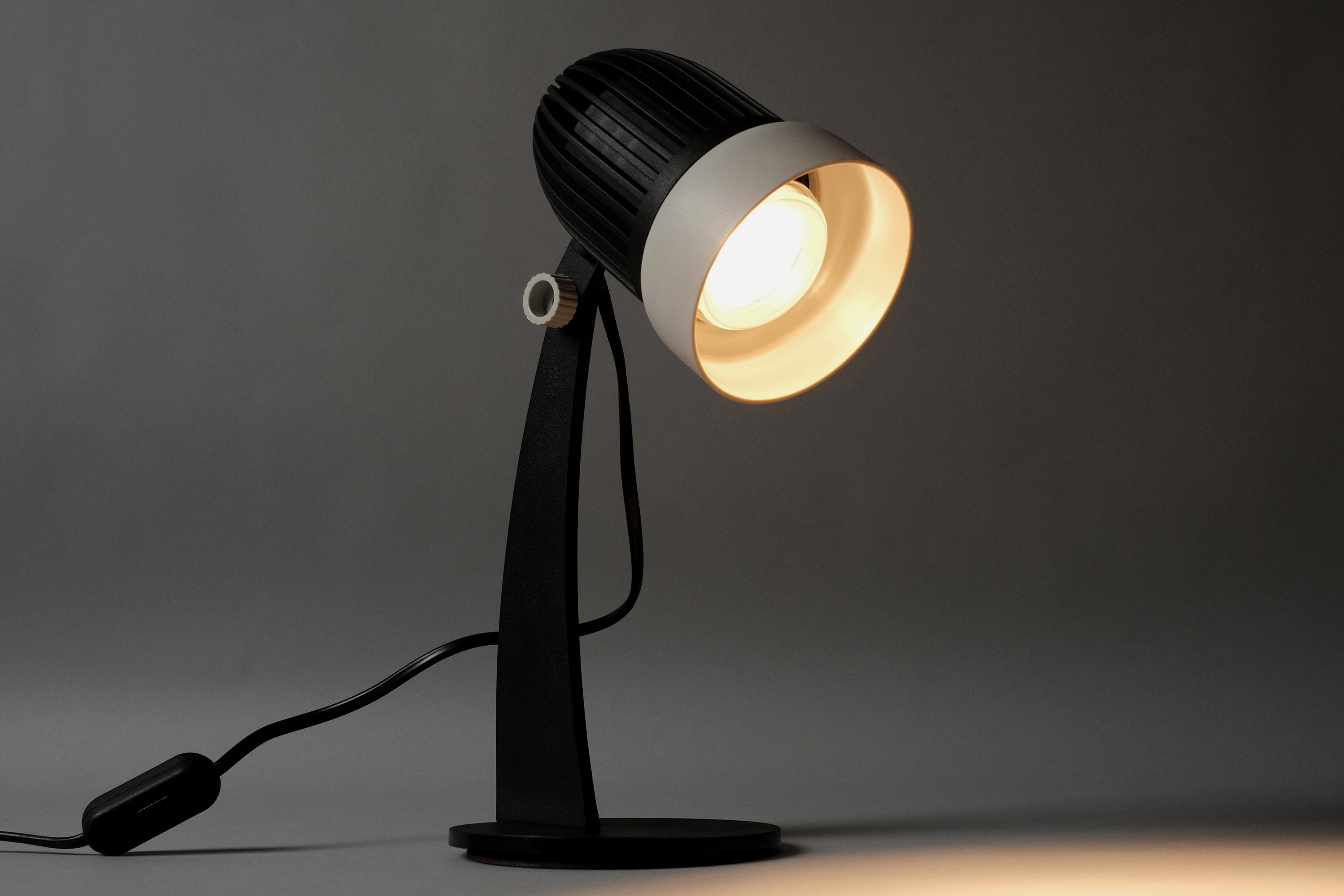 The vintage 1970s Aro Leuchte modernist adjustable desk lamp illuminated to demonstrate the focused task lighting from its conical reflector.