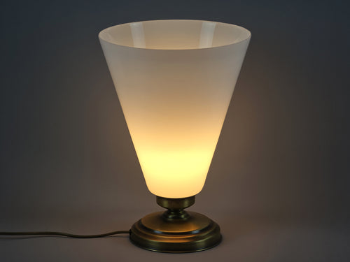 Vintage Art-Deco Revival table lamp with conical opaline glass cone, brass finish base, image showing amber lit glow of the lamp.
