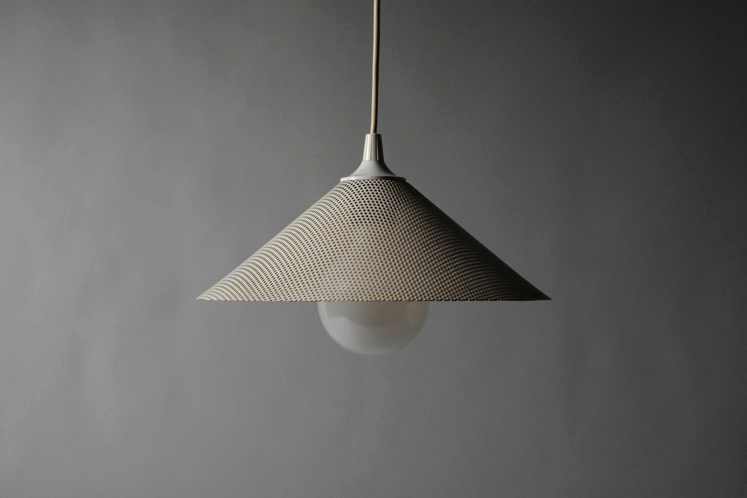 Full profile of 1980s Herda perforated pendant lamp, grey studio background