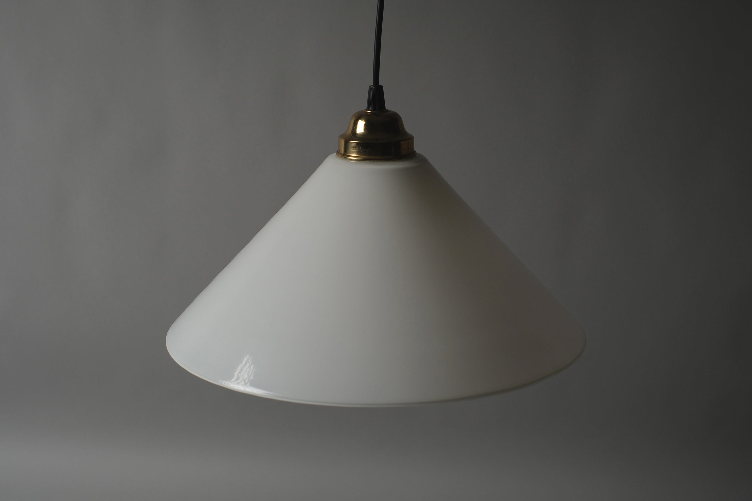 High-angle view of a 1980s vintage opal glass cone pendant lamp unlit, showing the full conical form and even ivory white surface of the opaline glass shade against a neutral background.
