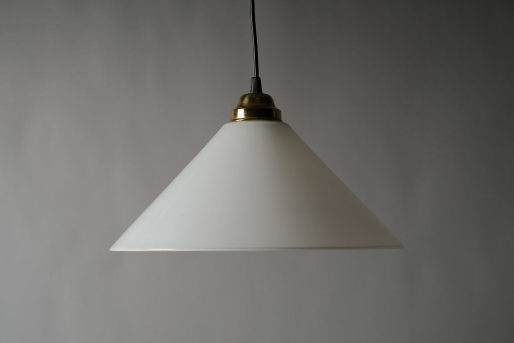 Profile view of a 1980s vintage opal glass cone pendant lamp, showing the clean conical silhouette and gold-plated brass fitting against a neutral grey background.