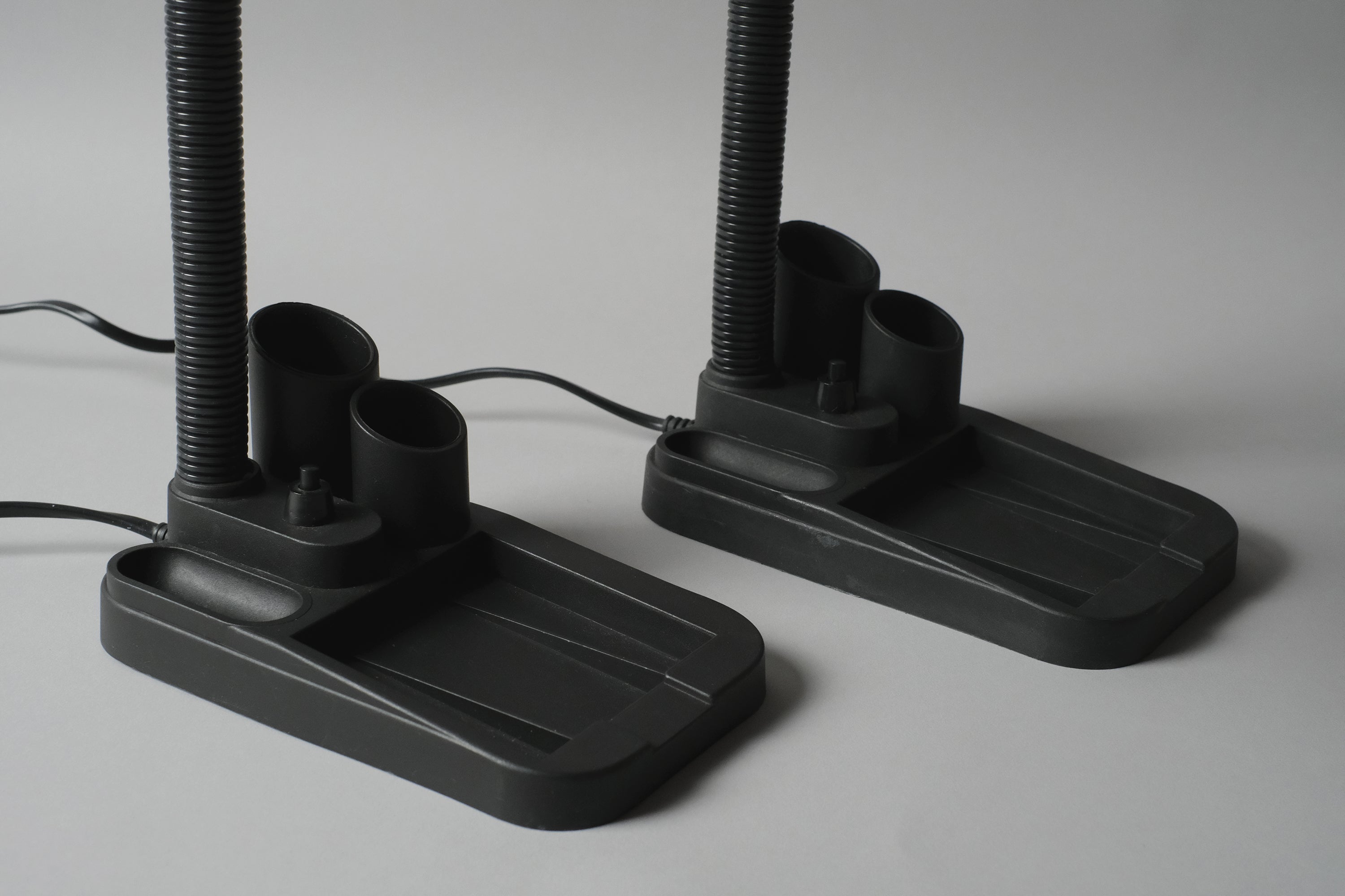 Macro close-up of the pair of Fase lamps' black plastic bases, which are built-in stationary caddies as well.