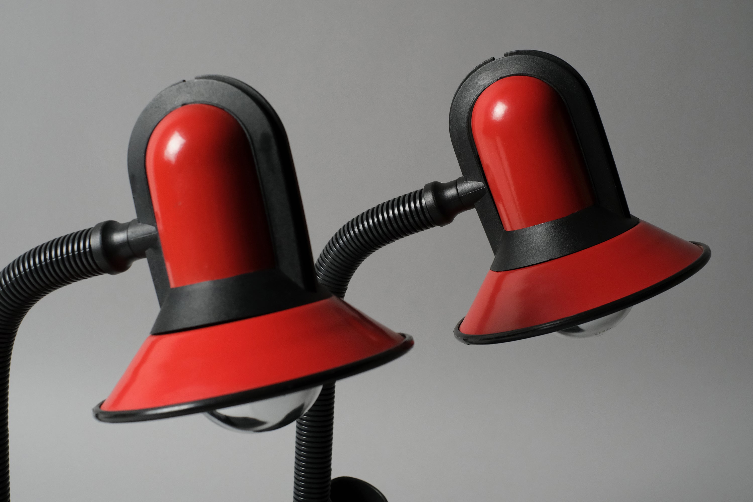 Macro close-up of the pair of Fase lamps' dome shade, they are in red lacquered metal with black plastic details.