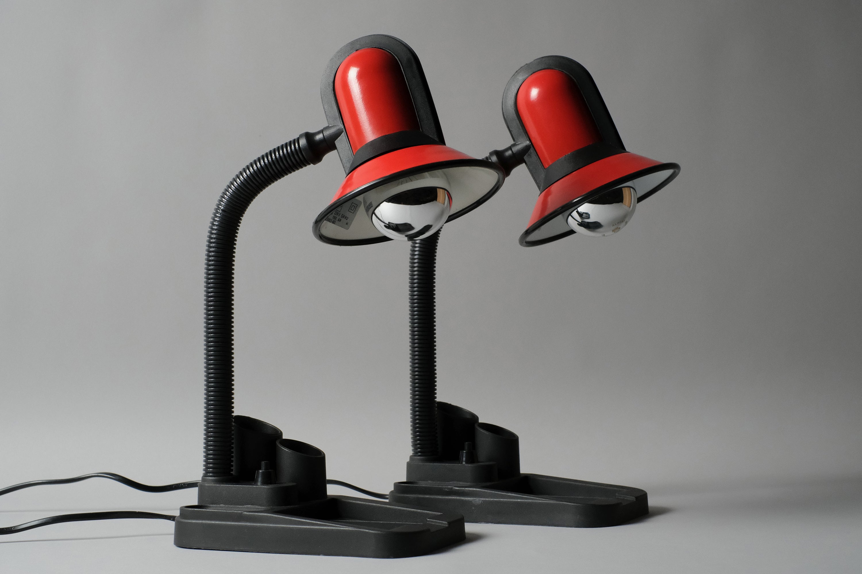 Pair of vintage 1980s gooseneck desk lamps with built-in stationary caddies by Fase Spain. The lamps have a black plastic base with red metal dome shades with black plastic detailing.