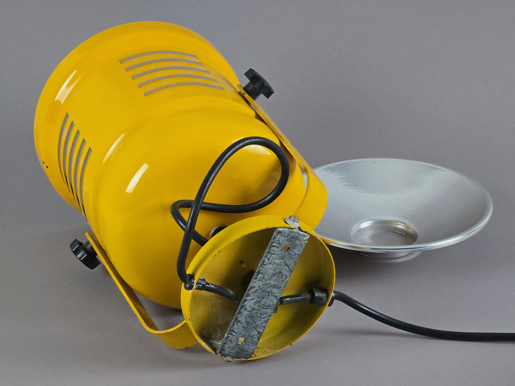 Rear image of a 1980s yellow wall projector showing the wall-mounting brackets and details of the round base.